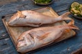 High-angle shot of two Ã¢â¬â¹Ã¢â¬â¹breams with cut stomachs on a tray on a wooden kitchen table